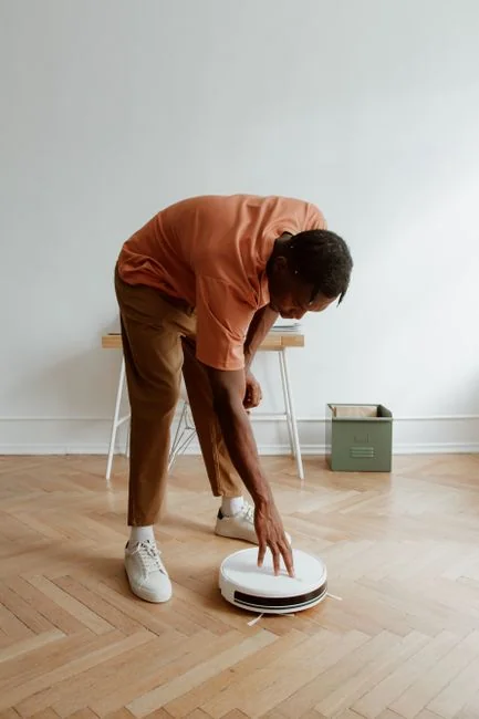 Side view of young ethnic male in uniform cleaning floor with mop while working in retro styled restaurant